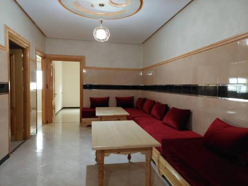 a living room with a red couch and tables at Cozy Al Hoceima Apt, Near Beach in Al Hoceïma