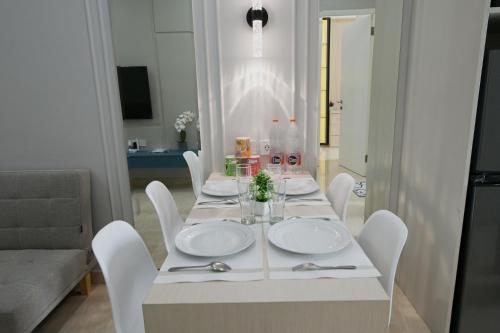 a white dining room table with white plates and chairs at Apartment Medan Podomoro City Deli by OLS Studio in Medan
