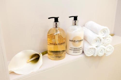 two bottles of soap and towels on a shelf at ApartHotel Vila Minka in Ljubljana