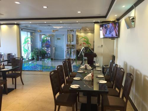 a dining room with tables and chairs and a television at Reem Hotel Apartments in Al Khuwayrīyah