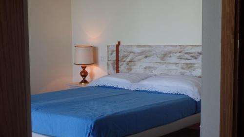 um quarto com uma cama com um cobertor azul e um candeeiro em Il Fienile Holiday Home em Le Fornacette