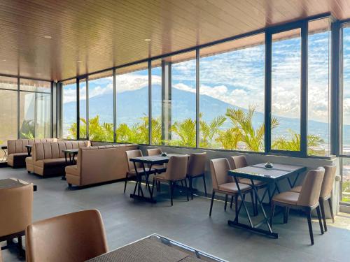 a restaurant with tables and chairs and windows at Samara Resort in Batu