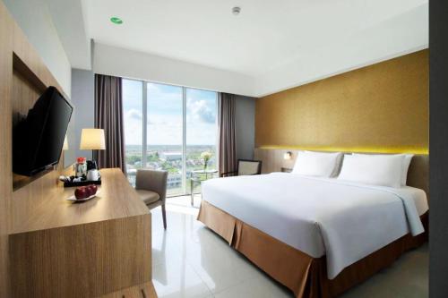 a hotel room with a large bed and a television at Grand Tan Banjarmasin Hotel & Convention Center in Banjarmasin