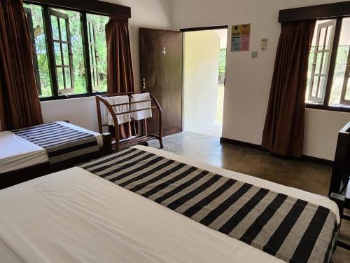 a bedroom with two beds and a chair and windows at Kemin Escapes - Yala in Tissamaharama