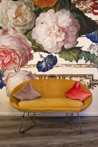 a yellow couch in front of a wall with flowers at Villa Delange in Landau in der Pfalz