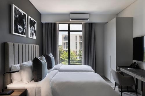 a hotel room with two beds and a window at The Capital Trilogy Menlyn Maine in Pretoria
