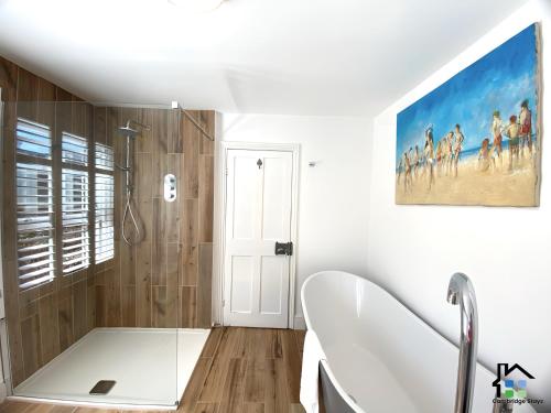 une salle de bain avec une baignoire blanche et une douche dans l'établissement Cambridge Stays 3BR house, easy walk to city center, 2 showers, garden, 2 free parking spaces, à Cambridge