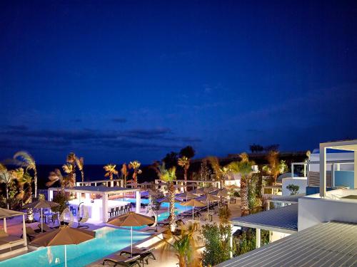 un complejo con piscina y sombrillas por la noche en Aurora Luxury Suites, en Imerovigli