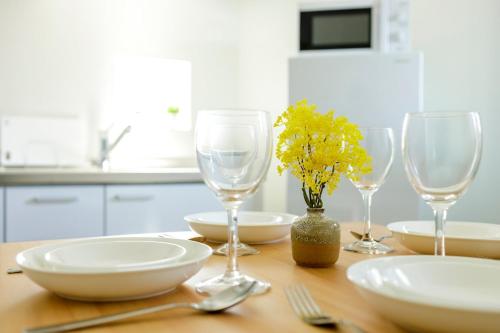 a table with three wine glasses and plates and yellow flowers at 楽宿 Nishi Shinjuku 017T in Tokyo