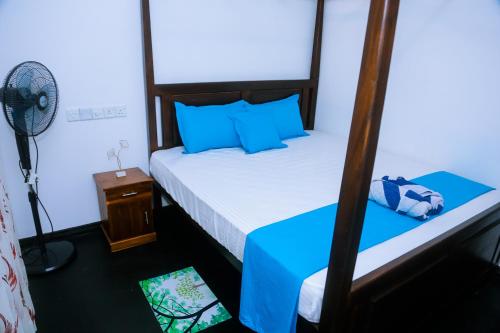 a bedroom with a bed and a fan in a room at Evergreen Cottage in Mirissa