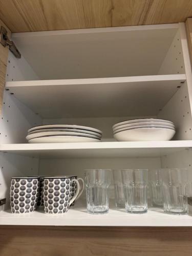 a white shelf with dishes and cups on it at Apartmán Lupa 2 in Nové Zámky