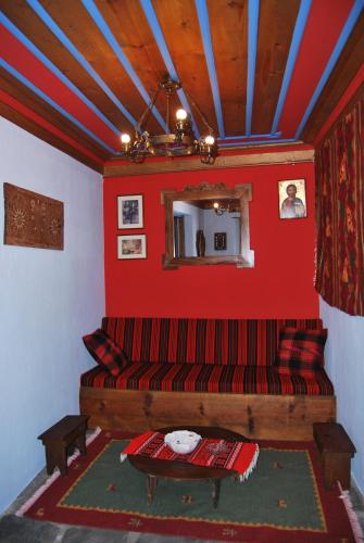 a living room with a red couch and a mirror at Tritoxo Guesthouse in Koukouli