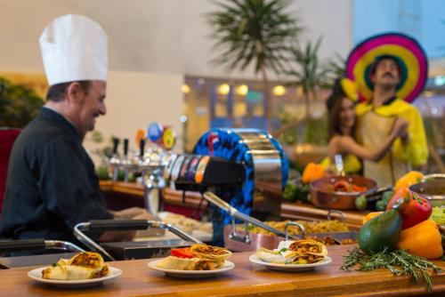 a man in a chef hat standing at a counter with food at Leonardo Club Eilat - All Inclusive in Eilat