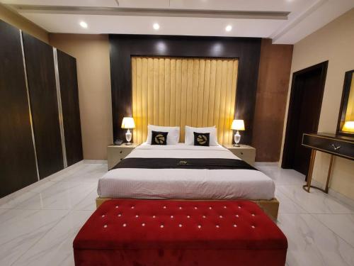 a bedroom with a large bed and a red ottoman at Palm tree suites in Lahore