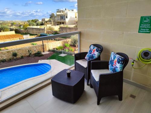 a balcony with two chairs and a swimming pool at Infinity view residence in Sannat
