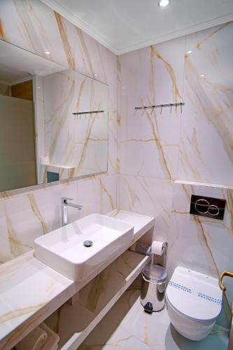 a white bathroom with a sink and a toilet at Kyparissia Beach Hotel in Kyparissia