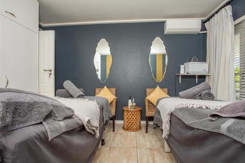 a bedroom with two beds and two mirrors on the wall at Thyme Wellness Spa and Guesthouse in Cape Town