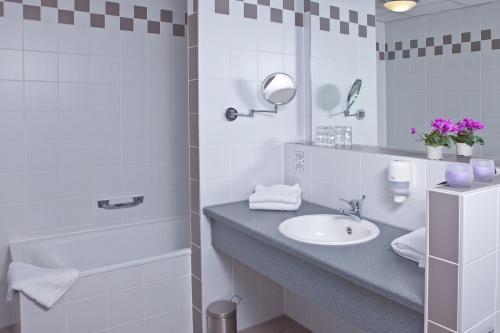 uma casa de banho com um lavatório, uma banheira e um espelho. em Hotel Strohofer em Geiselwind