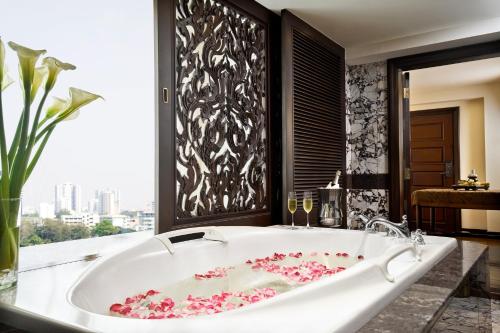 Anantara Siam Bangkok Hotel في بانكوك: حوض استحمام مع الزهور الزهرية في الحمام