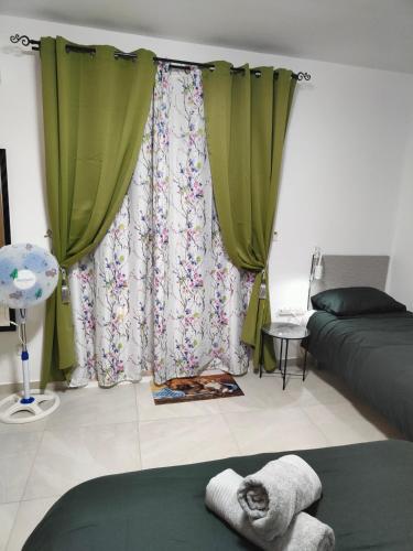 a bedroom with green curtains and a cat laying on a bed at Infinity view residence in Sannat