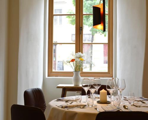 a table with wine glasses and a vase with flowers at Hotel Maribor & Garden Rooms in Maribor