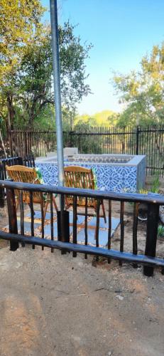 a bench in a park next to a fence at Amare Cabin in the bush with all your needs! in Marloth Park
