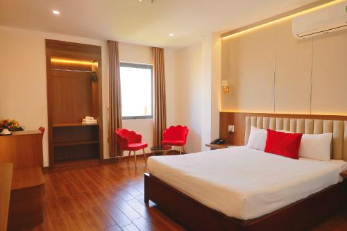 a hotel room with a bed and two red chairs at Le Centre Pleiku Hotel in Pleiku