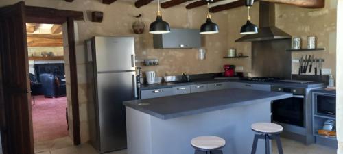 Una cocina con refrigerador y una encimera con taburetes. en La longère du golf, en Verneuil-sur-Indre