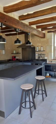 - une cuisine avec un comptoir et deux tabourets dans l'établissement La longère du golf, à Verneuil-sur-Indre