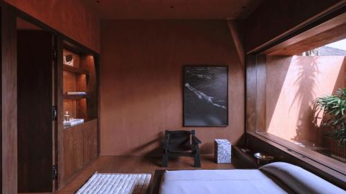 a bedroom with a bed and a chair in it at Further Hotel in Canggu