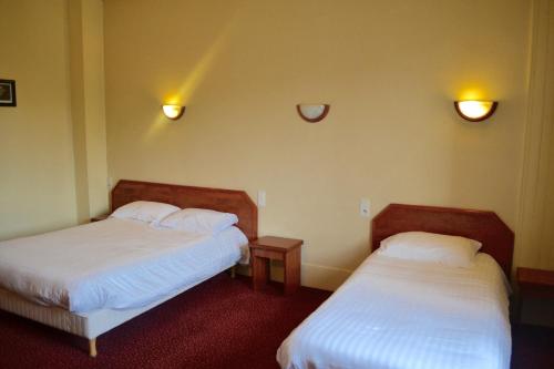 エヴルーにあるGrand Hotel De La Gareのベッド2台と壁に照明2つが備わる客室です。