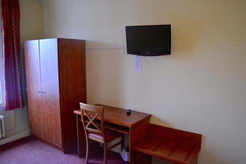 a room with a desk and a television on the wall at Grand Hotel De La Gare in Évreux