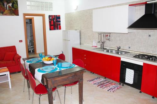 una cocina con armarios rojos y una mesa con un bol de fruta. en Ariel Apartment Ortigia Siracusa, en Siracusa