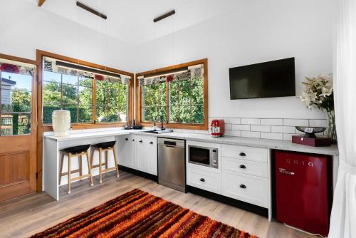 a kitchen with white cabinets and a tv on the wall at Cordwainer Eco Studio in Deloraine