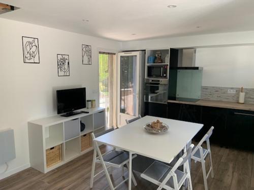 a kitchen with a table and a white table and chairs at Le petit bastidon gîte à Oppède avec piscine in Oppède