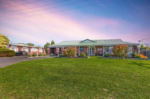 a house with a green lawn in front of it at Beachcomber Motel & Apartments in Apollo Bay
