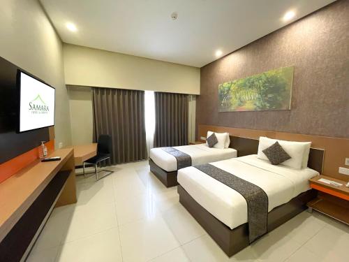 a hotel room with two beds and a flat screen tv at Samara Resort in Batu