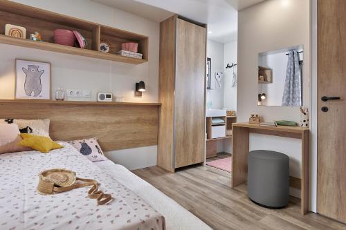 a small bedroom with a bed and a desk at CAMPING Bassin Arcachon - LES GOELANDS in Arès