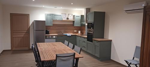 une cuisine avec des placards verts et une table avec des chaises dans l'établissement La maison du Vicomte, à Varennes