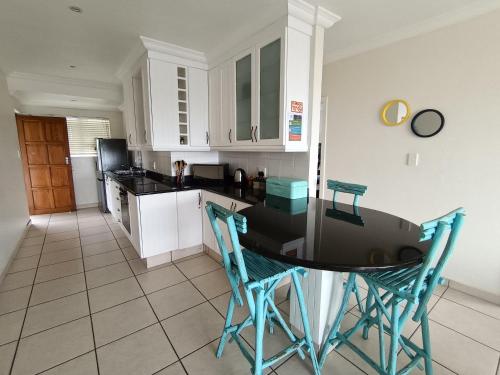 a kitchen with a table and chairs in it at Hello Holiday at 4 Boboyi Mangrove Beach Estate in Port Shepstone