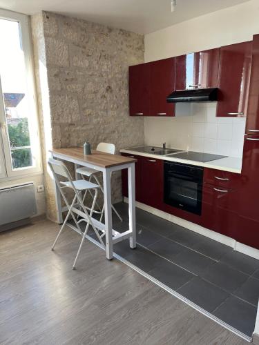 une cuisine avec des armoires rouges et une table et des chaises dans l'établissement Le Contemporain, à Rochefort