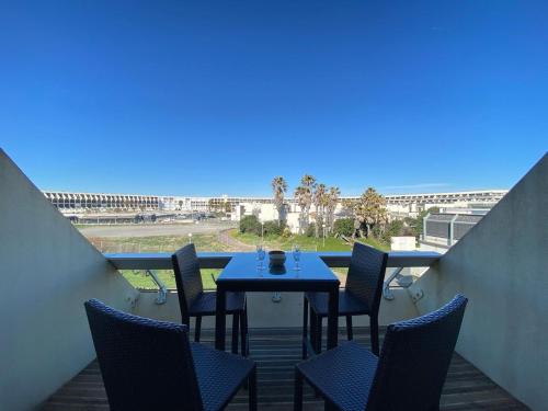 - un balcon avec une table et des chaises et la plage dans l'établissement L'Escale d'Héliopolis, Climatisé, Coeur du village, au Cap d'Agde