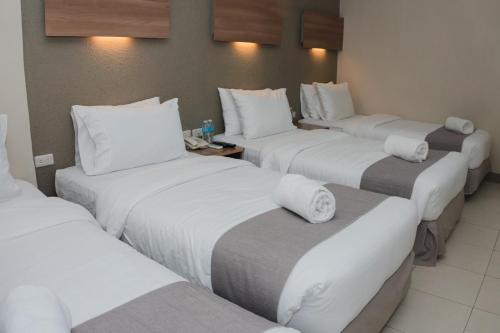 a hotel room with four beds with white pillows at The New View by Ecotel - Cebu in Cebu City