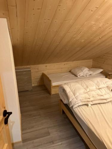 Cette chambre dispose de deux lits et d'un plafond en bois. dans l'établissement Gîte des flocons, à Morbier