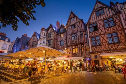 a group of people sitting at tables in front of buildings at Les Carnaux- Parking - Terrasse in Ballan-Miré