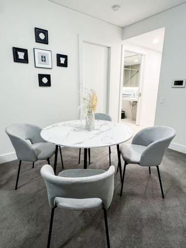 a dining room with a white table and chairs at Skyline Retreat in Olympic Park in Sydney