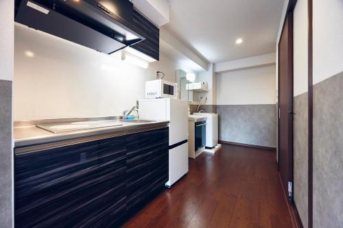 a kitchen with black cabinets and a white refrigerator at Montana Wing Yebisu in Osaka