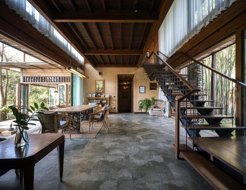 a room with a staircase and tables and windows at Nachan The Antique Courtyard in Chiang Khan