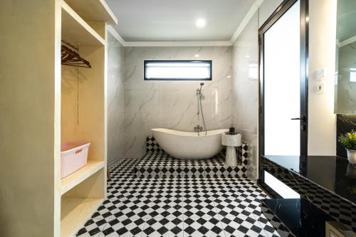 a bathroom with a tub and a black and white checkered floor at Villa Zilla by BaliSuperHost in Tegalalang
