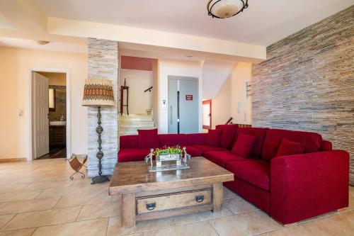 Una sala de estar con un sofá rojo y una mesa de café. en Greka Ioanian Maisonette - Pool & Seaview Bliss, en Agia Efimia